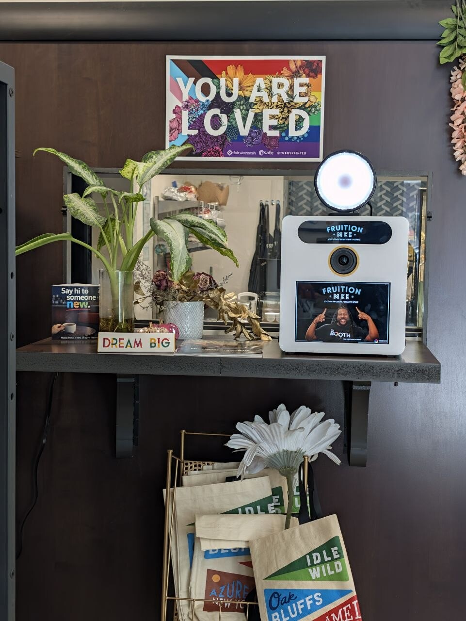 A Booth Mini installed on a shelf at Fruition MKE, its screen lit with the venue's branding